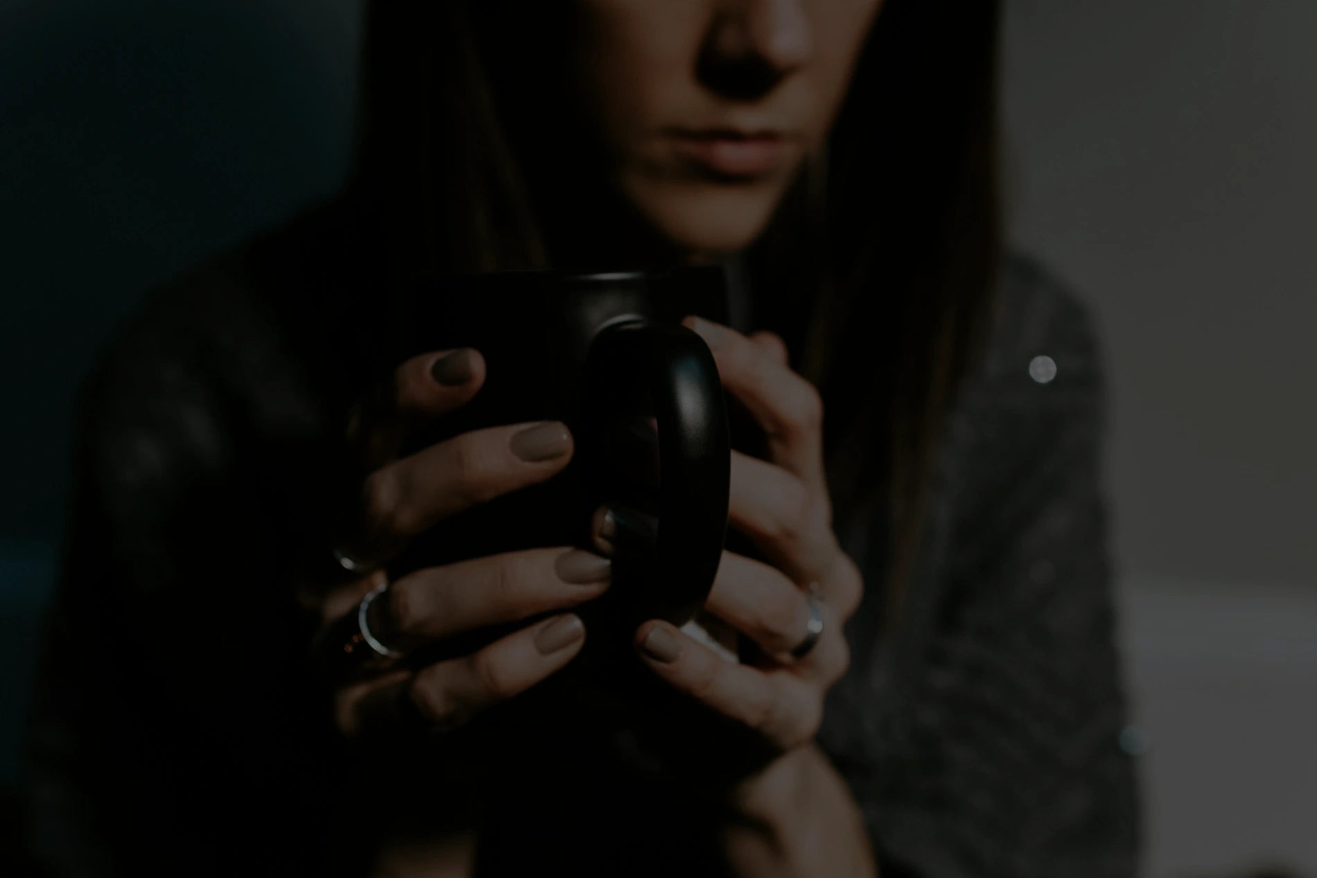 Person holding a black mug with a dark background