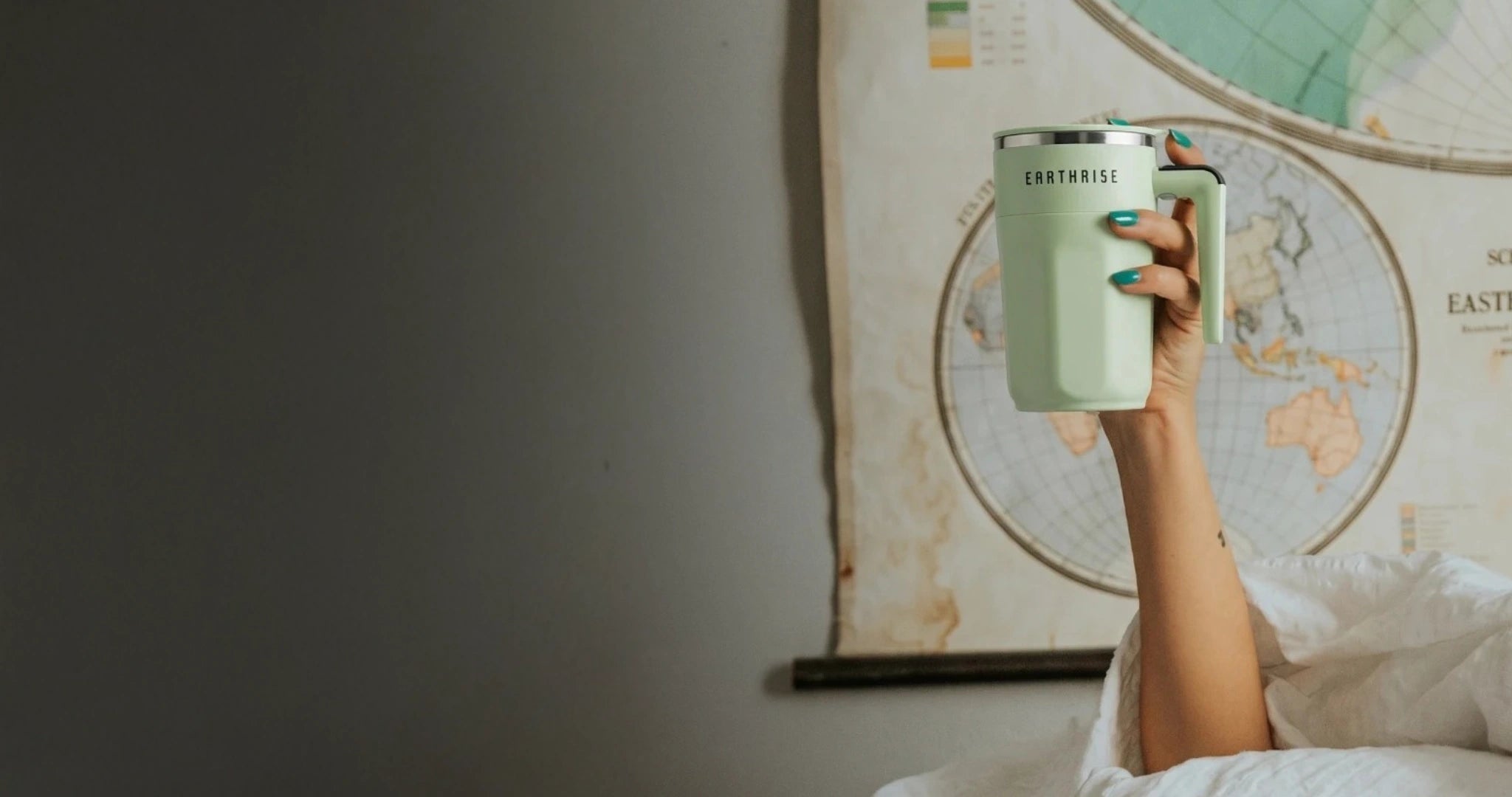 A person holding a mug of Earthrise high up in the air.