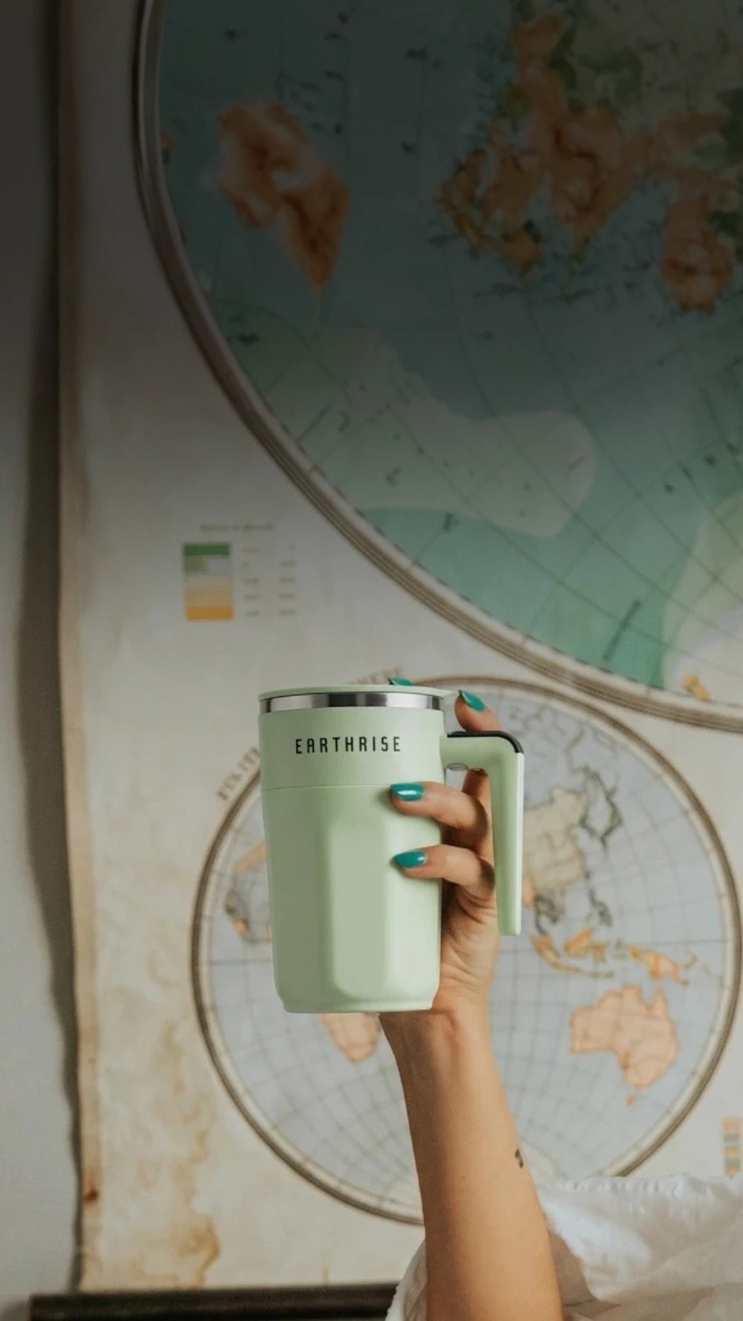 A person holding a mug of Earthrise high up in the air.